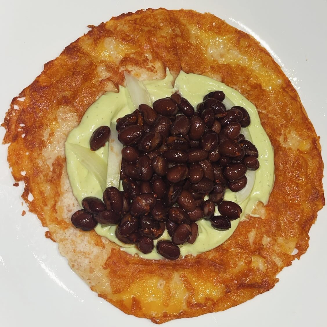 taco w cheese crust, avocado yogurt sauce, chili lime seasoned black beans, onio